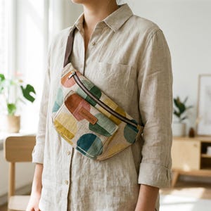 May include: A colorful fanny pack with a repeating pattern of large, overlapping circles in shades of pink, brown, green, yellow, and teal. The bag has a brown zipper and strap, and a small pocket with a "handmade" tag.