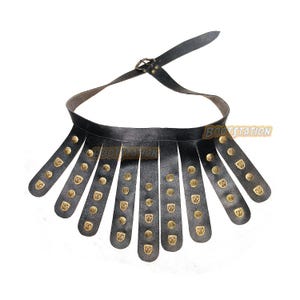 May include: Black leather Roman soldier belt with brass-colored studs and decorative plates. The belt has a buckle closure and a series of vertical leather strips. The text "BOOTSTATION" is visible on the belt.