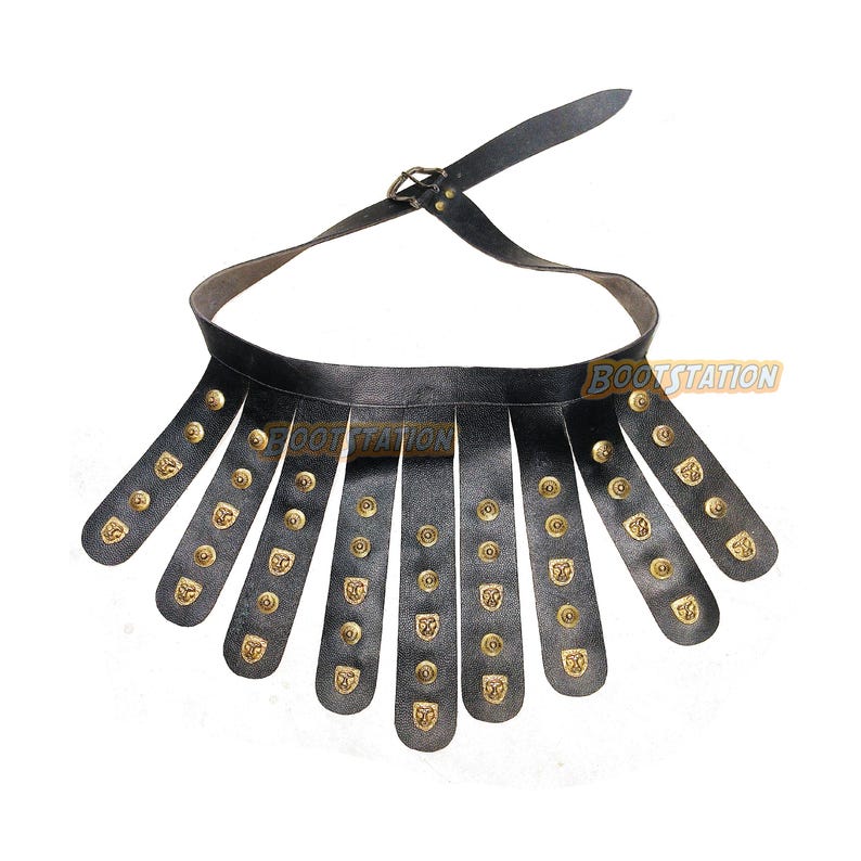 May include: Black leather Roman soldier belt with brass-colored studs and decorative plates. The belt has a buckle closure and a series of vertical leather strips. The text "BOOTSTATION" is visible on the belt.
