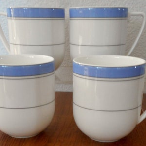 Puede incluir: Juego de cuatro tazas de cerámica blanca con un diseño de rayas azules y grises.