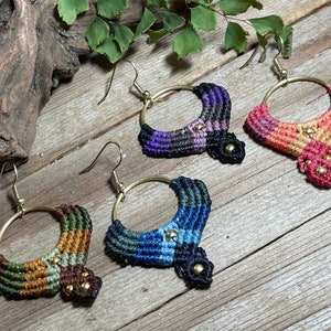 May include: Four pairs of colorful macrame earrings with gold hoops and beads. The earrings are made with a variety of colors, including purple, pink, orange, blue, green, and brown.