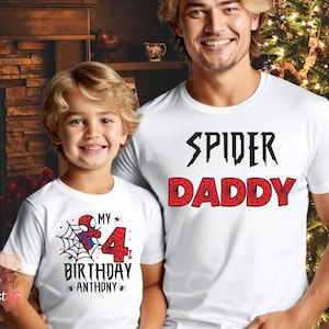 K&ouml;nnte beinhalten: Wei&szlig;e T-Shirts mit Spider-Man-Motiven. Eines zeigt "Spider Daddy" in Schwarz und Rot. Das andere hat eine Spider-Man-Grafik, ein Spinnennetz und den Text "My 4th Birthday Anthony".