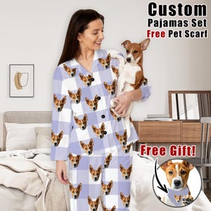 May include: A light purple and white plaid pajama set with a repeating dog face pattern. The pajama set includes a button-down shirt and pants. The image also includes the text "Custom Pajamas Set Free Pet Scarf Free Gift!"
