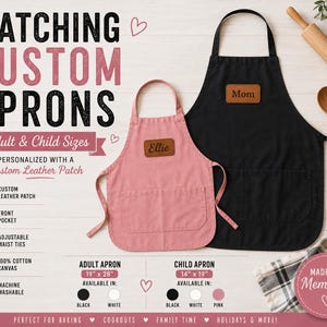 May include: A black apron and a smaller pink apron, each featuring a brown leather patch with custom text. The black apron has the text Mom, and the pink apron has the text Ellie. Both aprons include a front pocket and adjustable waist ties.