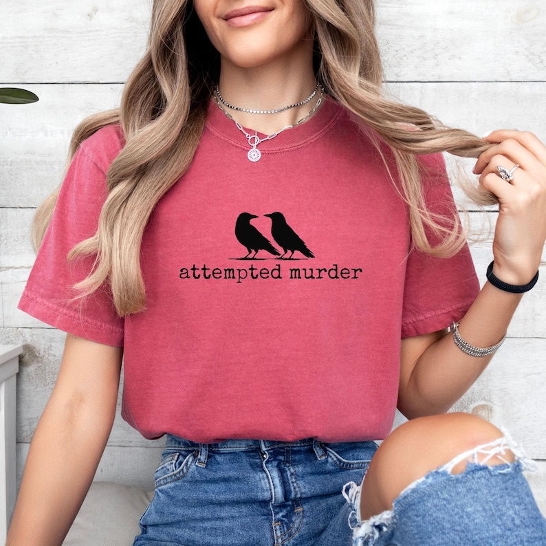 Pu&ograve; includere: T-shirt bordeaux con grafica nera di due corvi e la scritta "attempted murder". La maglietta &egrave; realizzata in materiale morbido ed &egrave; adatta per un abbigliamento casual. Il disegno &egrave; centrato sul davanti della maglietta.
