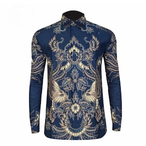 Puede incluir: Camisa de manga larga con fondo azul oscuro y un patrón ornamental y simétrico en tonos dorados y crema. La camisa presenta un cuello y puños clásicos, mostrando un diseño floral y aviar detallado.