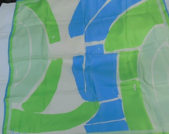 May include: A square silk scarf with an abstract design in shades of blue and green on a white background. The scarf has a white border with a thin blue and green trim. The design features irregular shapes.