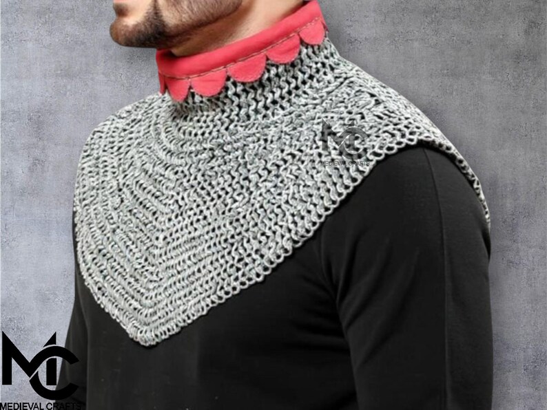 May include: A silver chainmail coif with a red scalloped collar. The chainmail is made of small, interlocking metal rings. The coif is worn over a black garment. The Medieval Crafts logo is visible in the lower left corner.