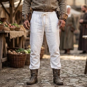 May include: White linen trousers featuring an elastic waistband with a central drawstring tie. The pants have a relaxed fit and are worn with a brown leather belt and dark brown leather boots, creating a simple and functional lower body garment.