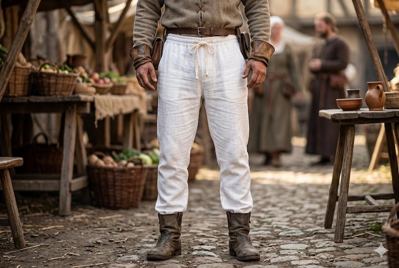 May include: White linen trousers featuring an elastic waistband with a central drawstring tie. The pants have a relaxed fit and are worn with a brown leather belt and dark brown leather boots, creating a simple and functional lower body garment.
