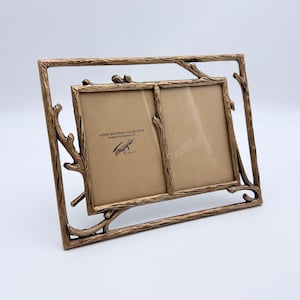 May include: A double photo frame with a bronze-colored metal finish and a textured branch-like design. The frame holds two 3.5 inch by 5 inch photos. The insert text reads: AGNES BOURNE COLLECTION designed exclusively for Tomografics 3.5 x 5.