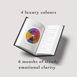 May include: An open black book with white pages, displaying a colorful wheel chart and lined pages. The text reads "4 luxury colours" and "6 months of steady emotional clarity."
