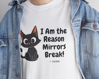 Op de afbeelding: Wit T-shirt met een cartoon zwarte kat met oranje oren en ogen. De tekst luidt "I Am the Reason Mirrors Break! I THINK". Het shirt wordt gedragen onder een blauw spijkerjasje.