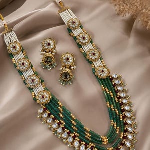 Conjunto de collar Kundan tradicional indio con cuentas verdes, hilos de perlas y pendientes Jhumka de piedra rubí. Joyería nupcial.