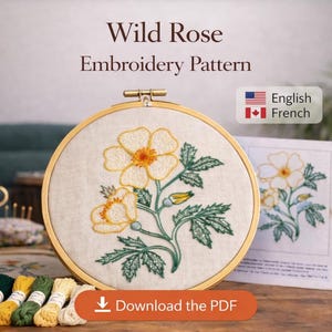 May include: An embroidery hoop with a floral design, featuring yellow and orange flowers with green leaves, is the focal point. The text "Wild Rose Embroidery Pattern" is above the hoop. The image includes embroidery floss and a "Download the PDF" button.