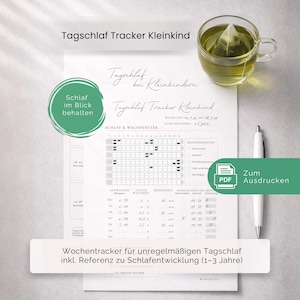 Könnte beinhalten: Ein weißes Blatt mit einem Tracker zur Überwachung des Schlafs von Kindern. Der Text enthält "Tagschlaf Tracker Kleinkind" und "Schlaf im Blick behalten". Eine Tasse Tee und ein Stift sind ebenfalls zu sehen.