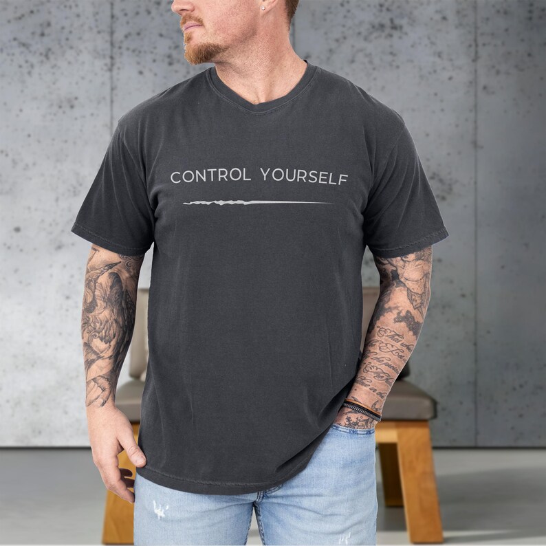 May include: Dark gray V-neck t-shirt with the text "CONTROL YOURSELF" in white, above a white horizontal line. The shirt is made of a soft material and has short sleeves.