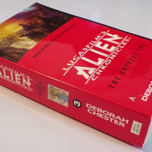 May include: A red paperback book titled "Lucasfilm's Alien Chronicles: The Crystal City" by Deborah Chester. The book cover features a landscape scene with a mountain range and a waterfall.
