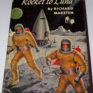 May include: A vintage science fiction novel cover featuring two astronauts in yellow spacesuits on the moon. The cover features the title "Rocket to Luna" and the author "Richard Marsten".