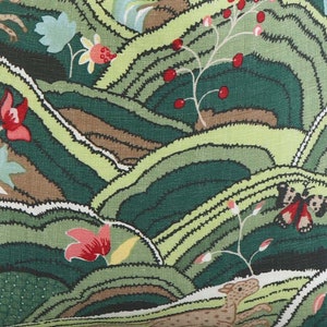 May include: A green fabric with a repeating pattern of stylized hills, flowers, butterflies, and a small animal. The hills are in shades of green, brown, and yellow. The flowers are red, pink, and white. The butterfly is red and black. The animal is brown and white.
