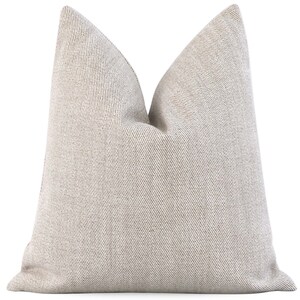 May include: A beige throw pillow with a subtle striped pattern. The pillow is made of a soft, textured fabric.