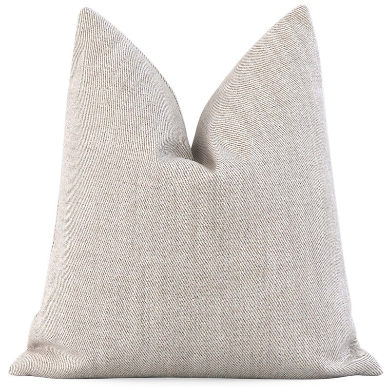 May include: A beige throw pillow with a subtle striped pattern. The pillow is made of a soft, textured fabric.