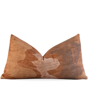 May include: A brown and white patterned throw pillow with a geometric design.