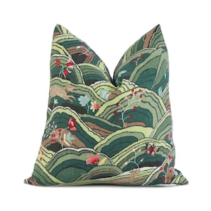 May include: Green pillow with a repeating pattern of stylized hills, flowers, and deer. The hills are a dark green, the flowers are red, and the deer are brown.