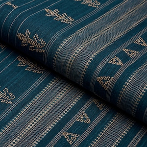 Puede incluir: Tela turquesa con un patr&oacute;n tejido de tri&aacute;ngulos dorados y &aacute;rboles estilizados. La tela tiene un brillo sutil y una superficie texturizada.