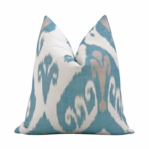 May include: A teal and white patterned throw pillow with a subtle beige design. The pillow is made of a soft, woven fabric.
