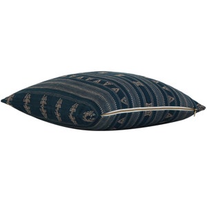 Puede incluir: Una almohada de tiro azul turquesa con un patr&oacute;n geom&eacute;trico en color beige claro. La almohada tiene una cremallera.