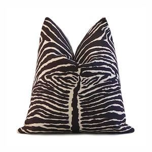 May include: A decorative throw pillow with a zebra stripe pattern. The pillow features a dark brown background with white stripes, creating a bold contrast. The pillow is square-shaped and appears to be made of a soft fabric.