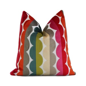 May include: A decorative throw pillow with a vibrant, colorful design. The pillow features a repeating pattern of large, scalloped shapes in shades of red, orange, gray, green, pink, and cream. The pillow is square and has a soft, textured appearance.