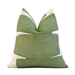 May include: A square decorative pillow with a green linen fabric and a white geometric design. The pillow has a soft, textured appearance and is designed for home decor.