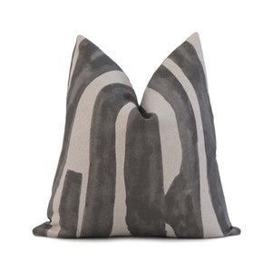 May include: A decorative throw pillow with a geometric pattern in shades of gray and beige. The pillow has a square shape and a soft, plush texture.