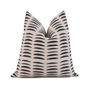 May include: A square decorative pillow with a cream-colored background and a repeating pattern of black, curved lines. The pillow has a soft, textured appearance and is designed for home decor.