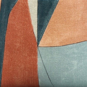 May include: Geometric pattern fabric with a mix of brown, orange, and blue colors. The fabric has a textured surface.