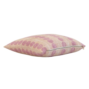 May include: A pink and beige throw pillow with a geometric pattern of circles and lines. The pillow has a zipper closure.