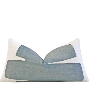 May include: Rectangular decorative pillow with a white background and a geometric design in shades of blue-gray. The pillow has a soft, textured appearance, and the design is abstract and modern. The pillow is designed for home decor.