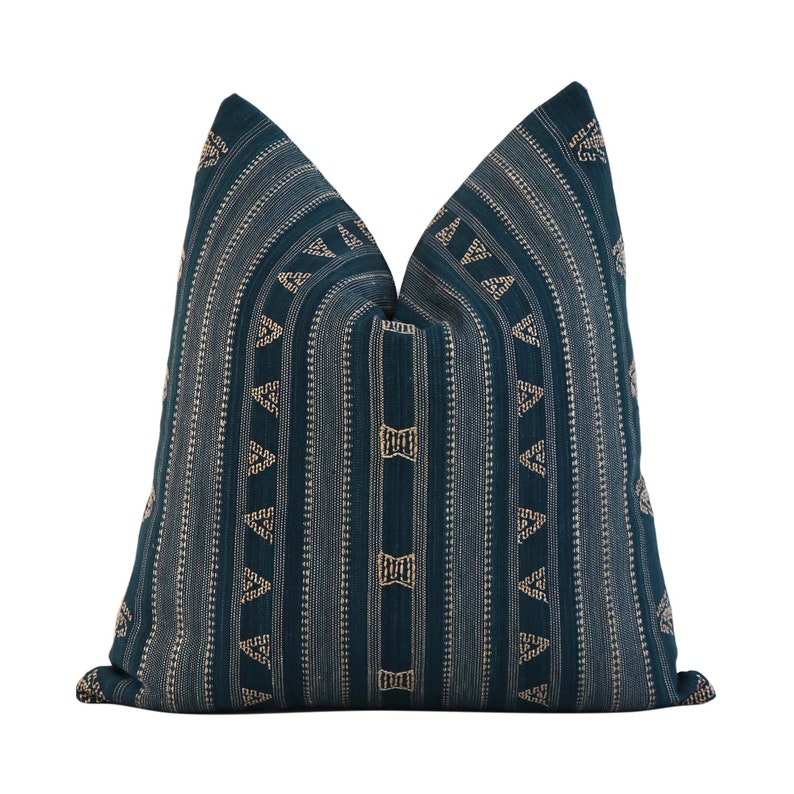 Puede incluir: Coj&iacute;n de tiro azul teal con un patr&oacute;n geom&eacute;trico de tri&aacute;ngulos y l&iacute;neas doradas.