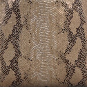 May include: Close-up of a snakeskin pattern. The design features a mix of tan, brown, and off-white scales, creating a textured, reptile-like appearance. The pattern is detailed and intricate, with variations in colour and texture.