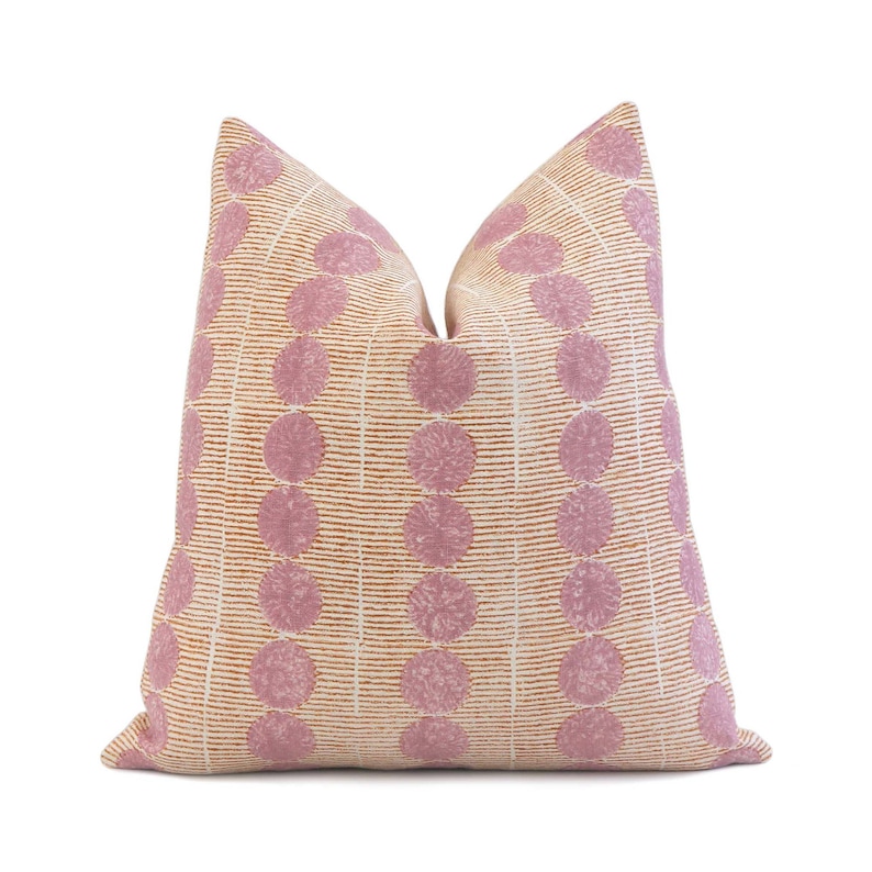 May include: A pink and orange patterned throw pillow with a geometric design. The pillow has a square shape and is made of a soft fabric.