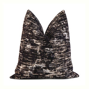 May include: Black and white patterned throw pillow with a geometric design. The pillow is made of a soft, textured fabric.