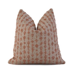 May include: A soft, textured throw pillow with a geometric pattern in shades of beige and terracotta.