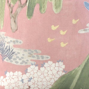 May include: A pink fabric with a floral pattern. The fabric features white flowers, green leaves, and yellow birds. The background is a light pink color.