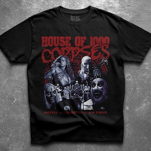 Puede incluir: Camiseta negra con el texto rojo "HOUSE OF 1000 CORPSES" y un gráfico de personajes de la película. La camiseta también incluye el texto "WRITTEN AND DIRECTED BY ROB ZOMBIE".