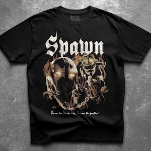 Könnte beinhalten: Ein schwarzes Kurzarm-T-Shirt mit einem Grafikdruck der Figur Spawn, umgeben von Ketten und Flammen. Das Wort Spawn ist in großen weißen Buchstaben oben aufgedruckt, und der Text Born in Darkness, Sworn to justice steht darunter.