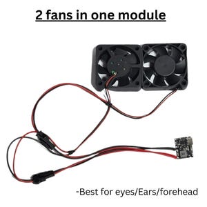 May include: A black module with two fans, connected by red and black wires, and a small circuit board. The text "2 fans in one module" is at the top, and "-Best for eyes/Ears/forehead" is at the bottom.