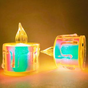 以下が含まれることがあります： リアルな炎の効果を持つ2つのLEDキャンドル。キャンドルは、虹色のインテリアを備えた透明な滴るワックスデザインです。炎は透明で尖った形をしており、ベースは温かみのある黄色です。