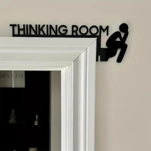 May include: Black metal sign that reads "THINKING ROOM" above a white door frame. A silhouette of a person sitting and thinking is on the right side of the sign.